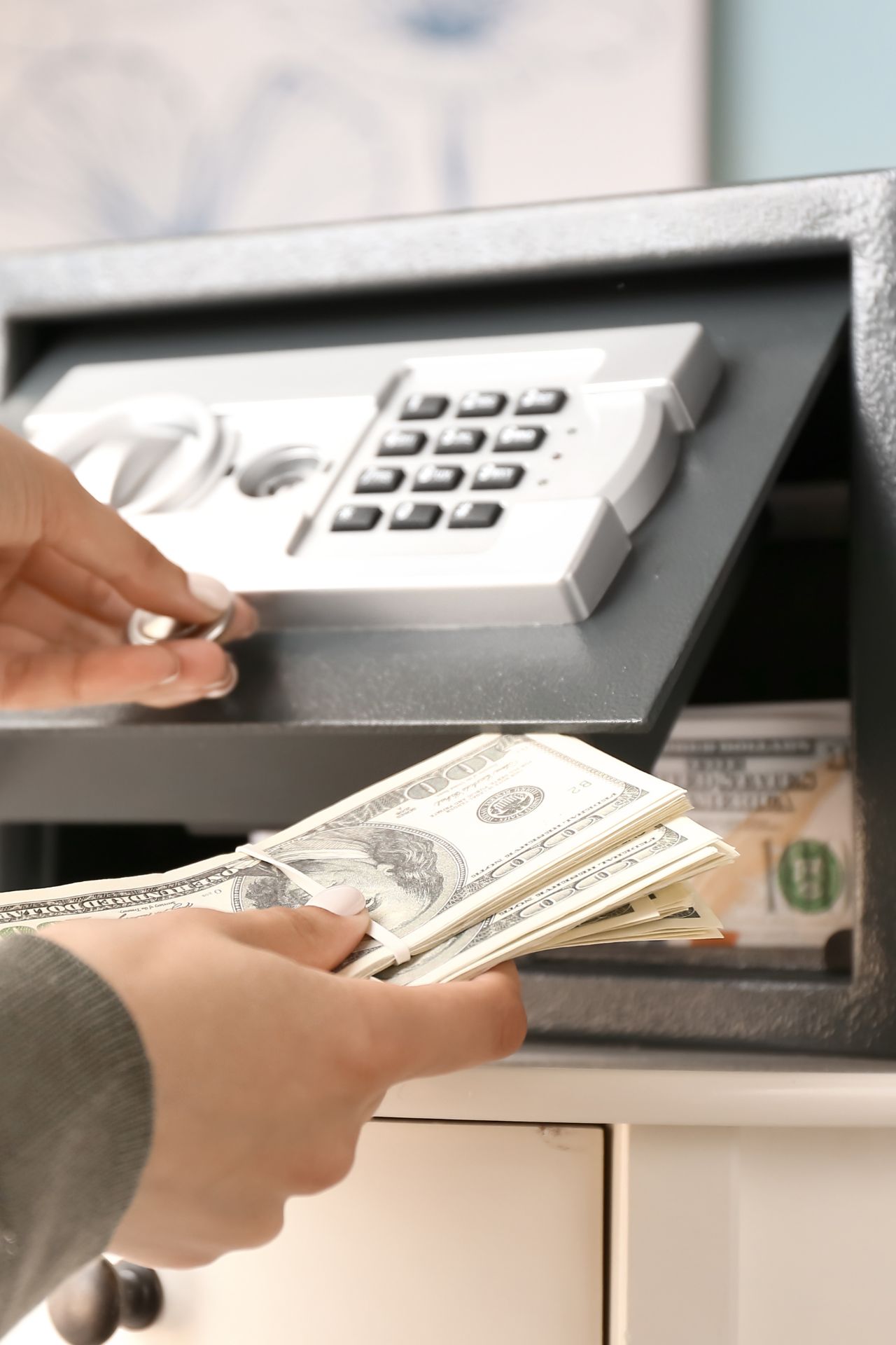Frau mit Geld in der hand vor einem Tresor mit Pin-Code